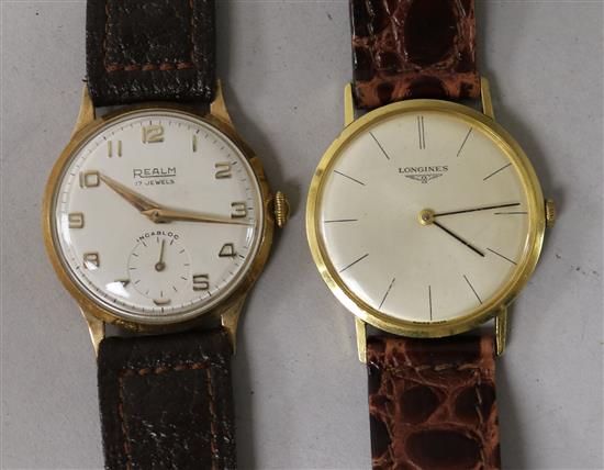 A gentlemans 18ct gold Longines manual wind wrist watch and a yellow metal Realm wrist watch.